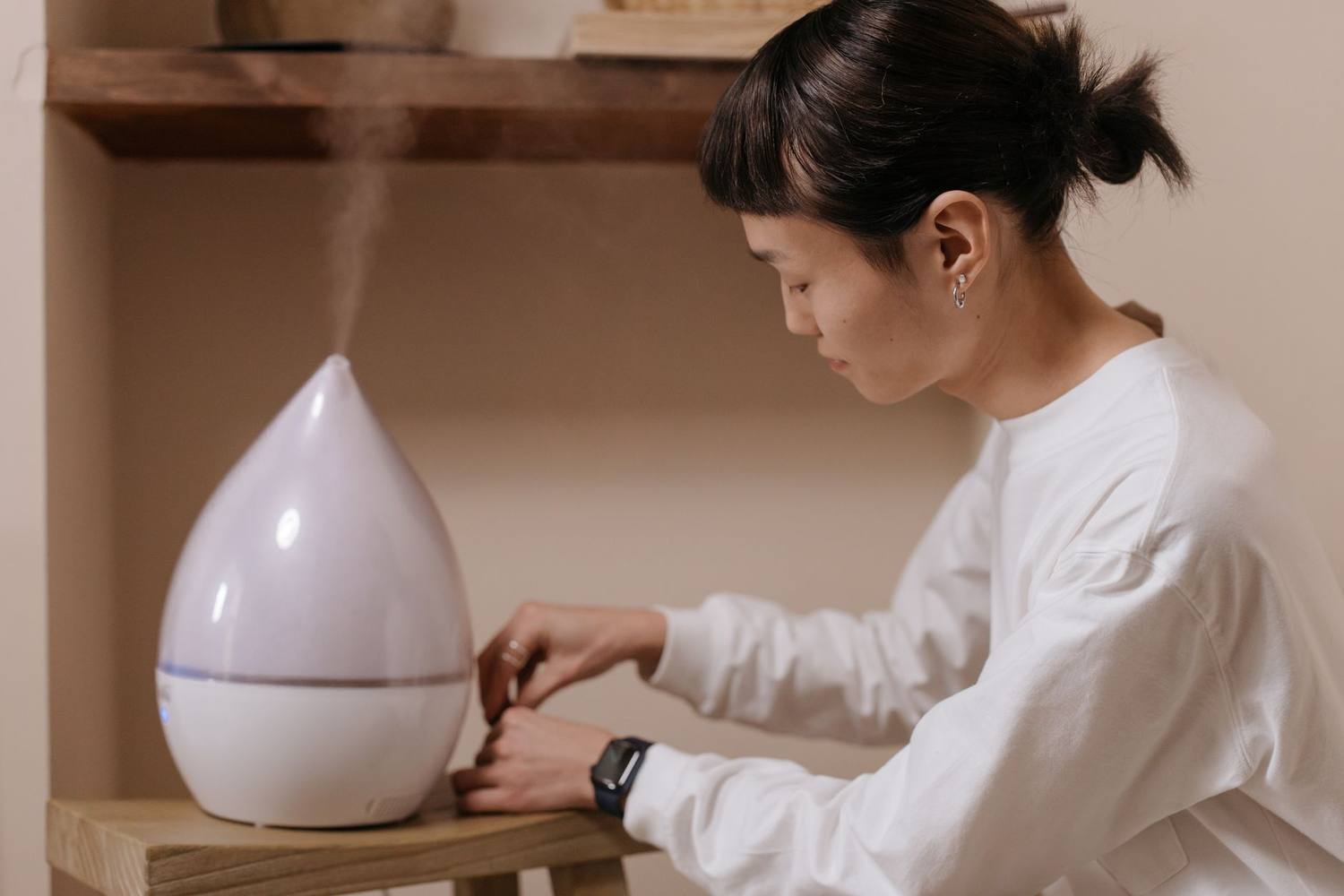 棚の上の加湿器を操作する人